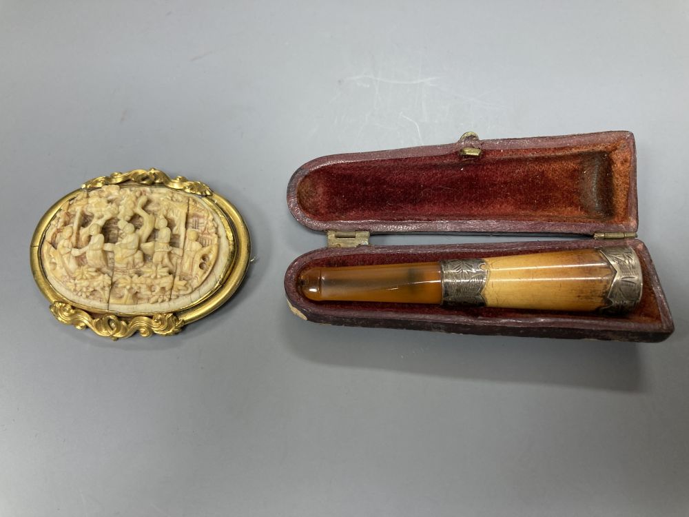 A Chinese gilt metal and ivory oval brooch, 55mm and a silver mounted clay and amberoid cheroot holder.